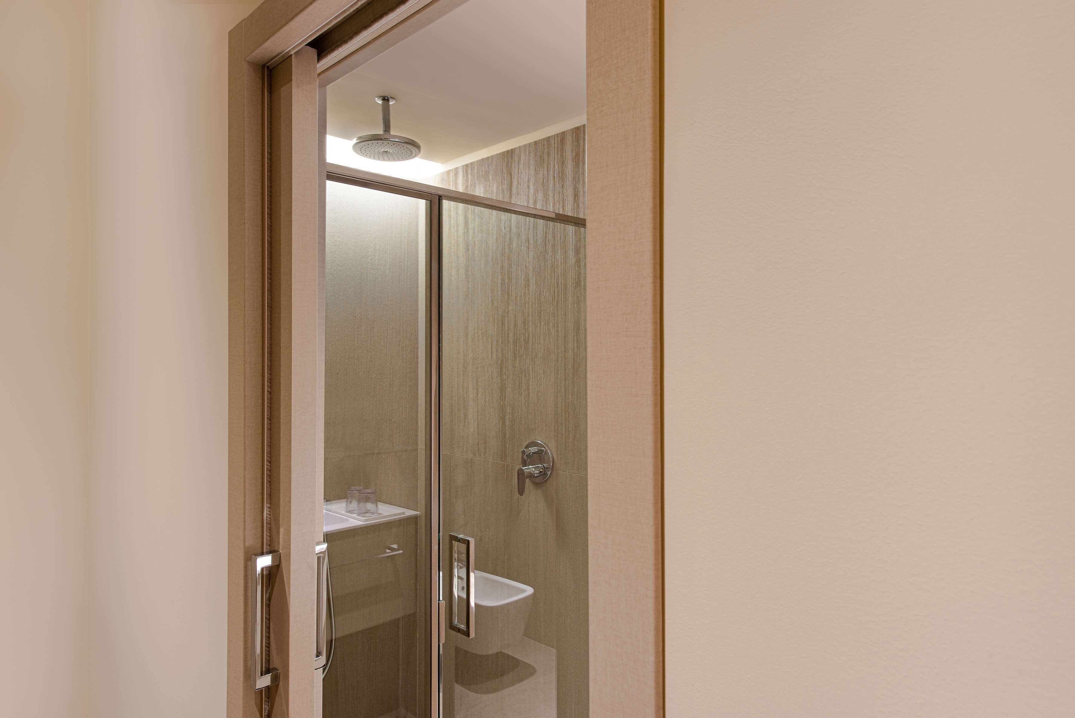 A modern bathroom with a glass shower enclosure, a sink, and a toilet.