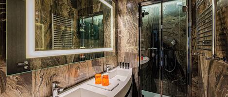 A modern bathroom with a large mirror, two sinks, and a glass-enclosed shower.