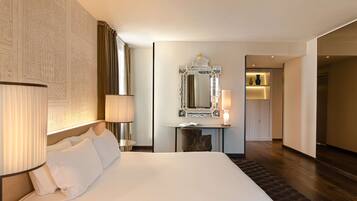 Quarto de hotel com uma cama grande, uma escrivaninha com espelho e uma luminária.