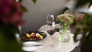 Une table ronde sur laquelle se trouvent une assiette de fruits, deux verres à vin et un vase de fleurs.