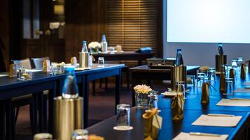 A conference room with a long table set for a meeting, equipped with microphones, nameplates, and various beverages.