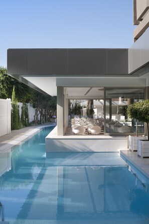 Ein moderner Poolbereich mit freiem Blick auf den Pool, Liegestühle und eine verglaste Terrasse.
