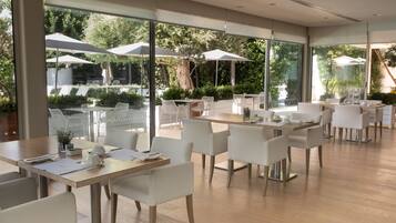 A modern dining area with tables and chairs, large windows, and outdoor umbrellas.