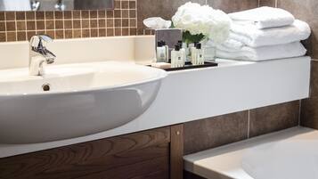 A modern bathroom with a large white sink, a mirror, and a stack of white towels.