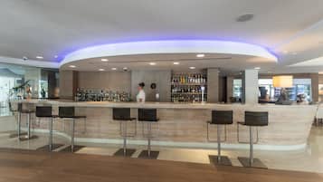 Zona de bar moderna con una barra curva, taburetes y una variedad de botellas.