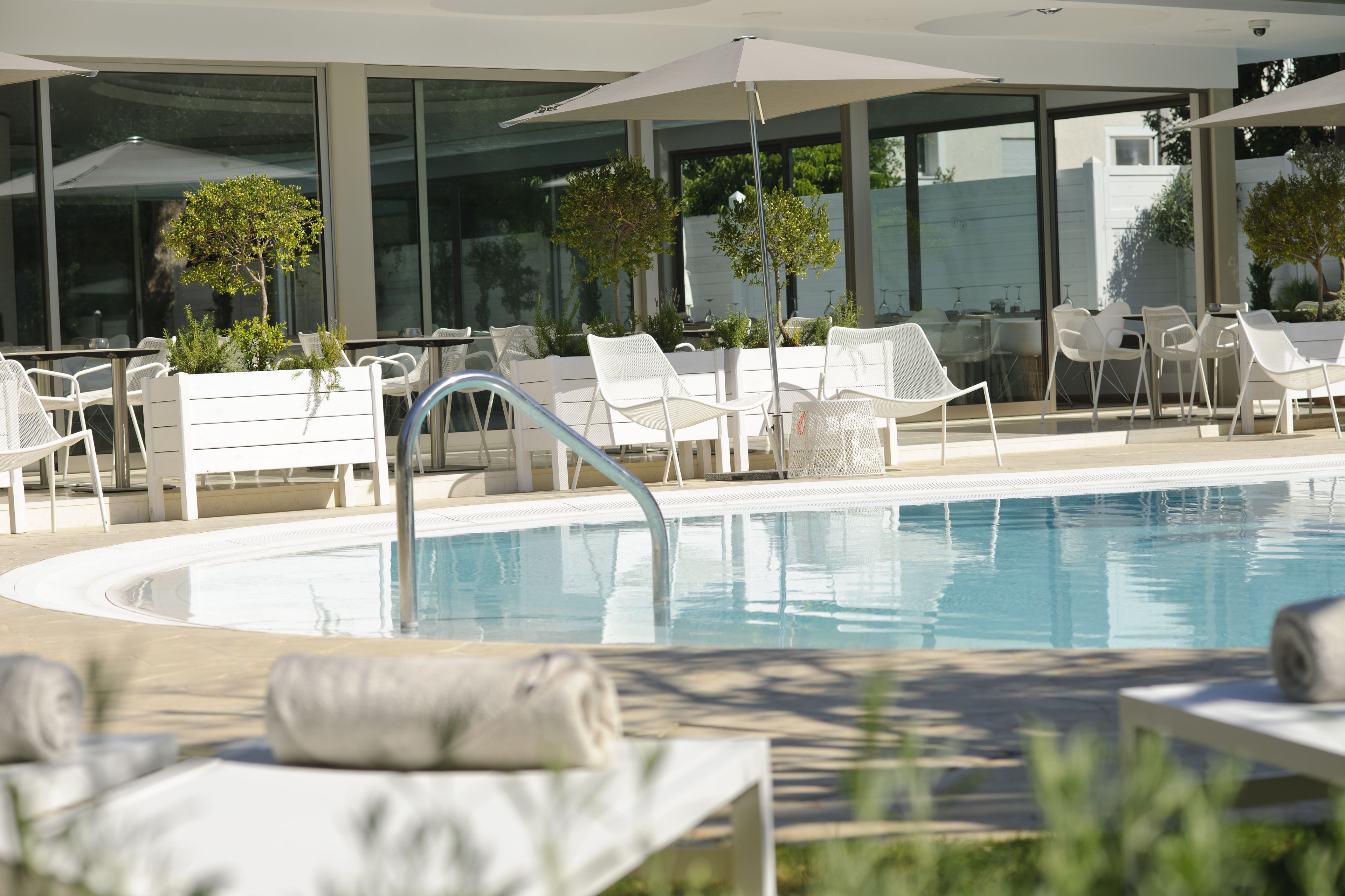 Un área junto a la piscina con sillones de descanso, sombrillas y una piscina.