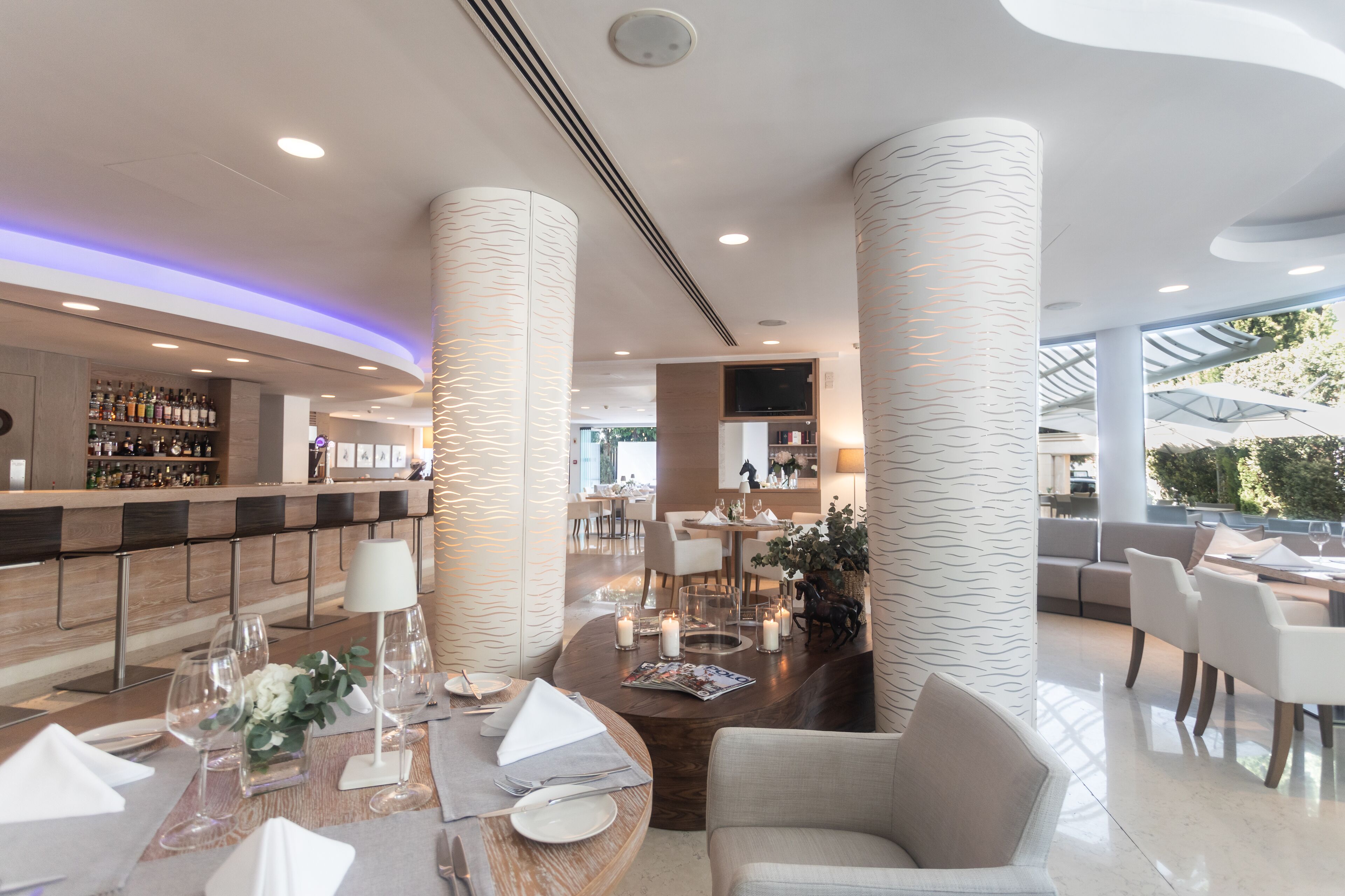 Un hall d’hôtel moderne doté d’un bar, de coins salon et d’un téléviseur.