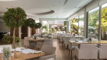 Un restaurante moderno con plantas de interior, mesas y sillas de madera.
