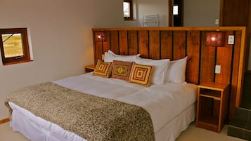 Een slaapkamer met een houten hoofdeinde, een bed met witte lakens en decoratieve kussens.