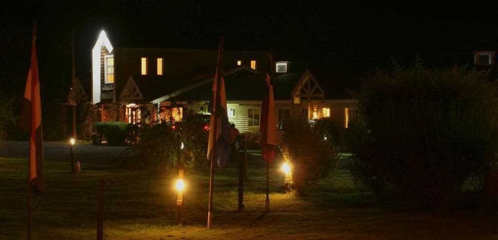 Una casa con la entrada iluminada y banderas al frente.