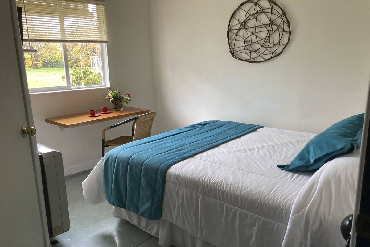 A bedroom with a bed, a desk, and a chair.