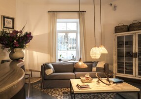 Una sala de estar acogedora con un sofá, una mesa de centro, una lámpara y una estantería.