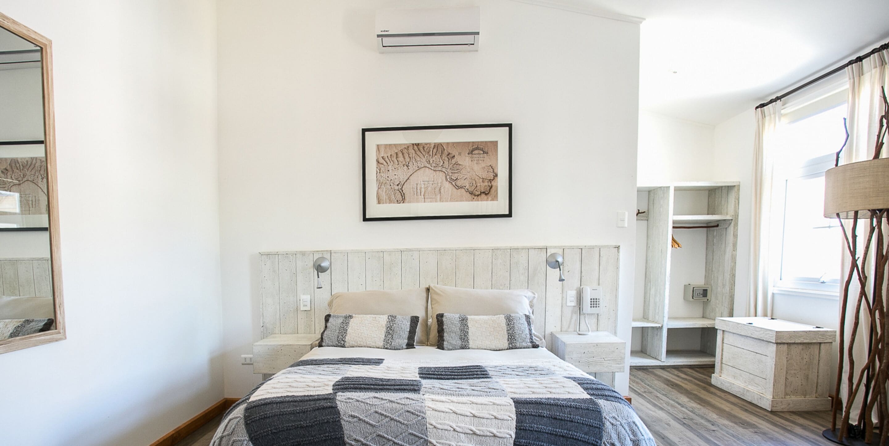 Un dormitorio con una cama, una mesita de noche, un teléfono en la pared y un mapa enmarcado.