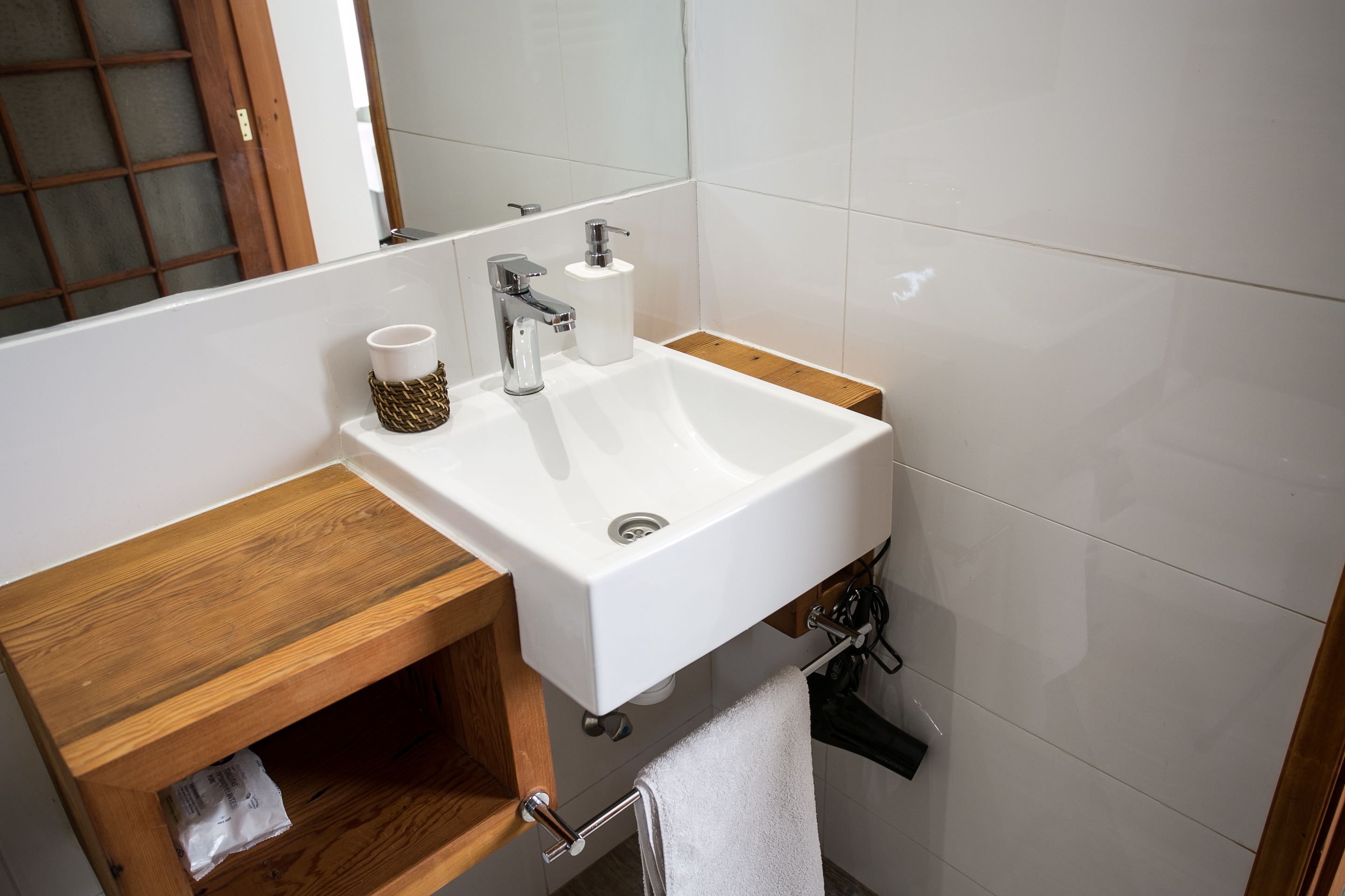 Une salle de bain avec un lavabo blanc, un meuble-lavabo en bois et un porte-serviettes.