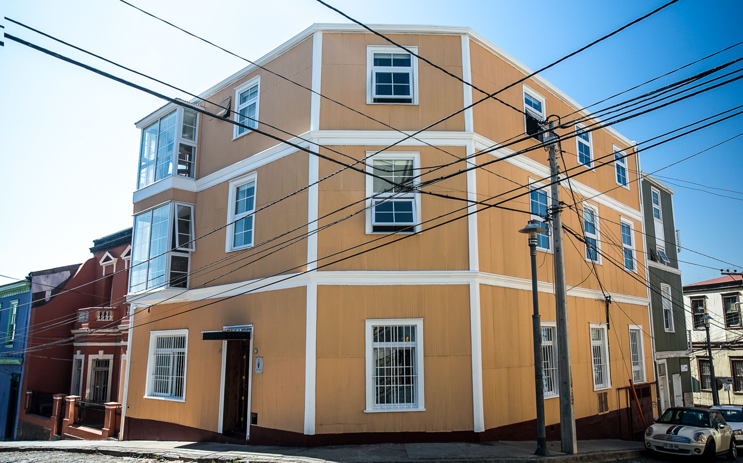 A multi-story building with a brown facade, multiple windows, and visible power lines.
