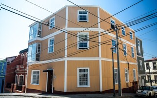Un edificio de varios pisos con fachada marrón, múltiples ventanas y líneas eléctricas visibles.