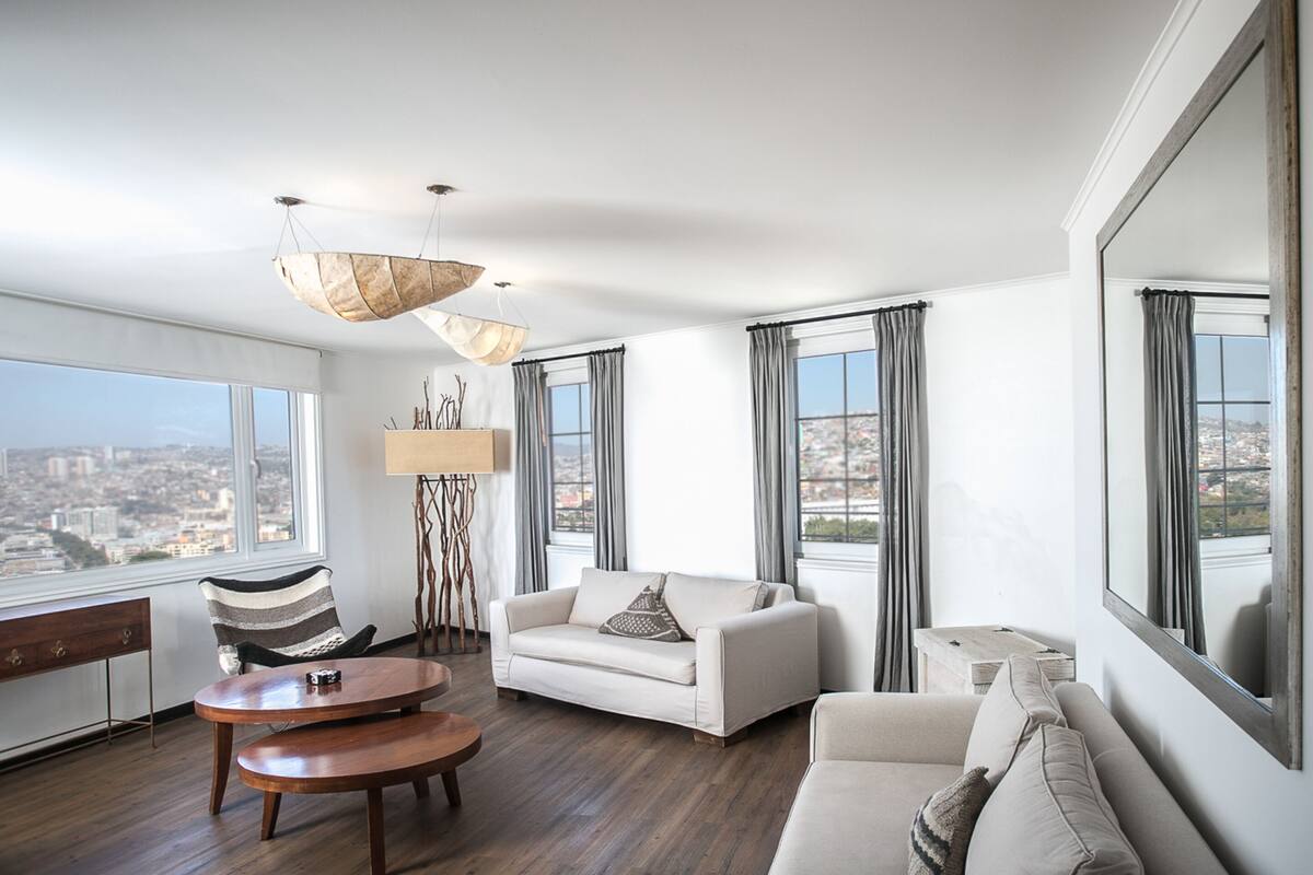 Un salon spacieux avec une grande fenêtre, un canapé, une table basse et un lampadaire.