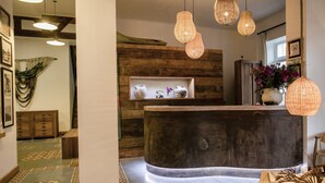 A reception area with a curved counter, pendant lighting, and a display shelf with decorative items. - Casa Galos Hotel & Lofts (Valparaiso)