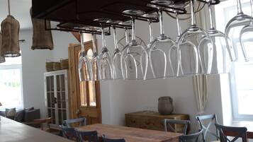 A dining area with a wooden table and blue chairs, a hanging wine glass rack, and a wooden cabinet in the background.
