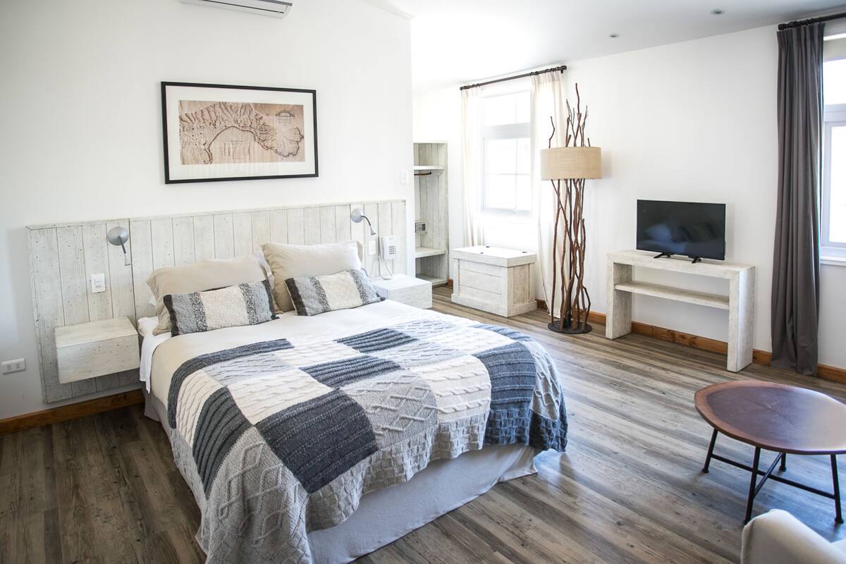 Une chambre à coucher comprenant un lit, une table de chevet, une lampe, une télévision et une petite table.