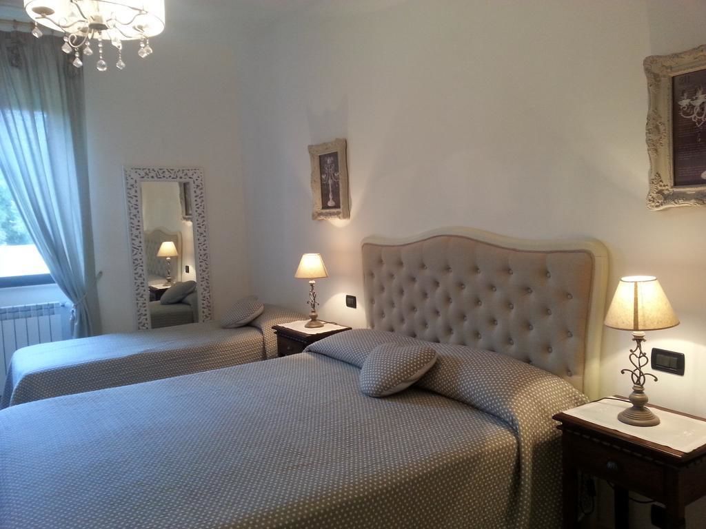 A hotel room with two beds, a chandelier, a mirror, and a framed picture on the wall.
