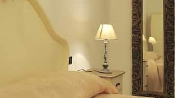 Una cama bien hecha con una lámpara y un espejo sobre una mesita de noche.