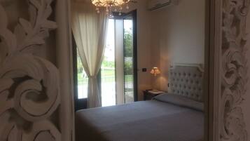 Un dormitorio con una cama grande, un candelabro, un equipo de aire acondicionado y vistas al exterior.