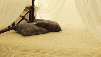 A bed with a canopy, two pillows, a lamp, and a bedside table.