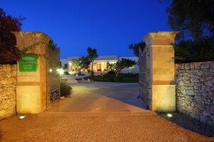 Una casa de campo llamada Willaria, con un portón de piedra, un camino y una entrada bien iluminada.