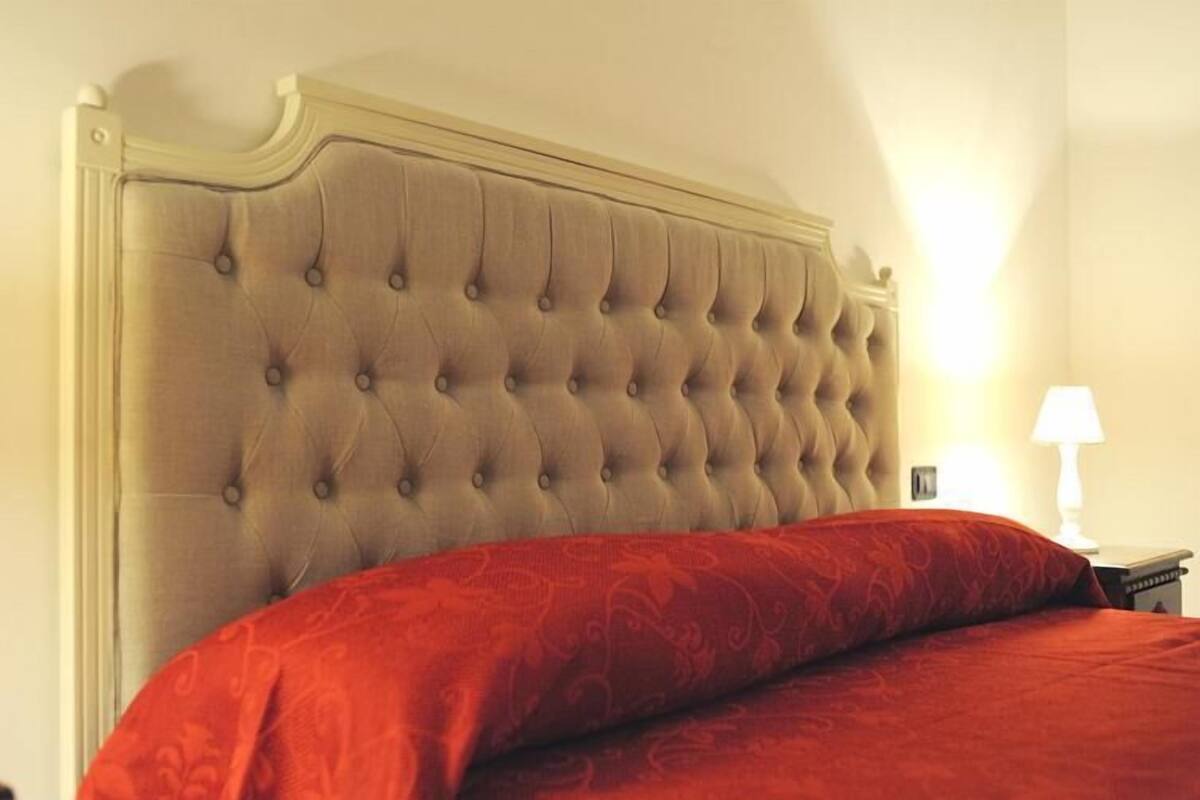 A bed with a tufted headboard and a red patterned bedspread.