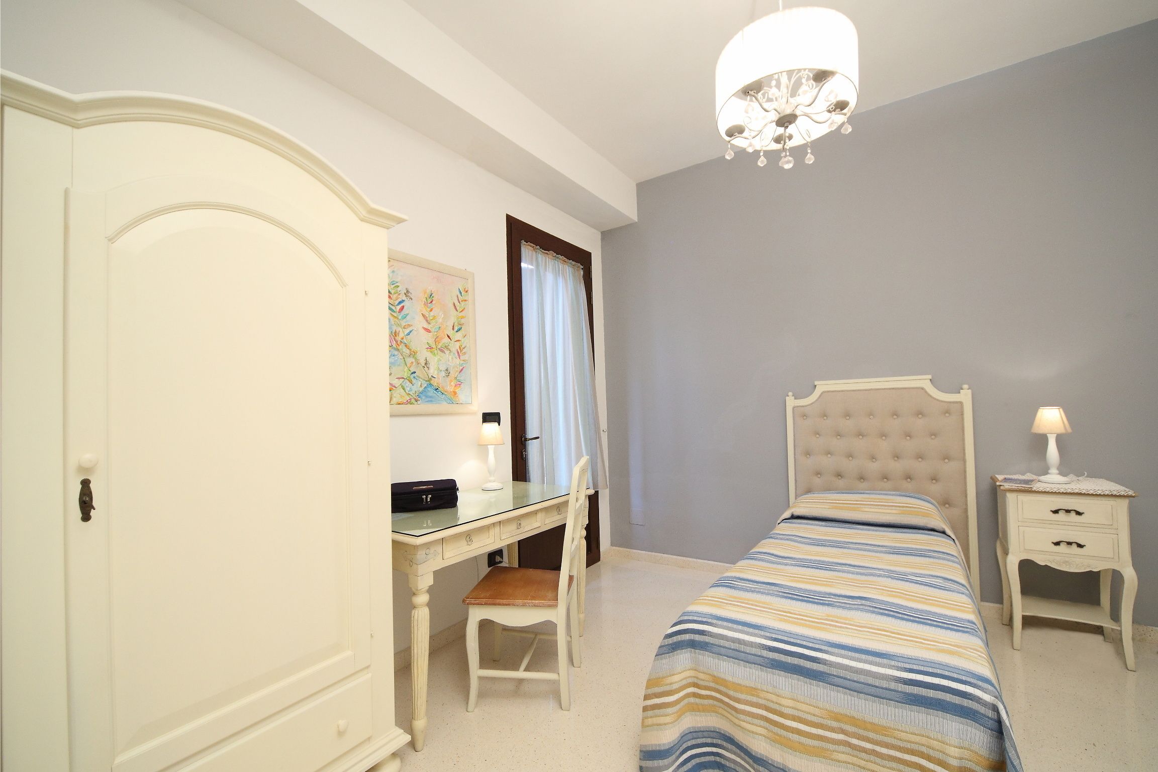 Una camera da letto con un letto, una scrivania, una sedia, un armadio e un comodino.