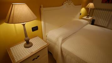 A neatly made bed with a white headboard, a bedside table with a lamp, and a wall-mounted light.