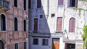 An open courtyard with a fountain, surrounded by historic buildings with arched windows and doors. - Ca Maria Callas (Venice)