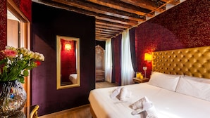 A hotel room with a large bed, a mirror, a vase with flowers, and a wooden ceiling. - Ca Maria Callas (Venice)
