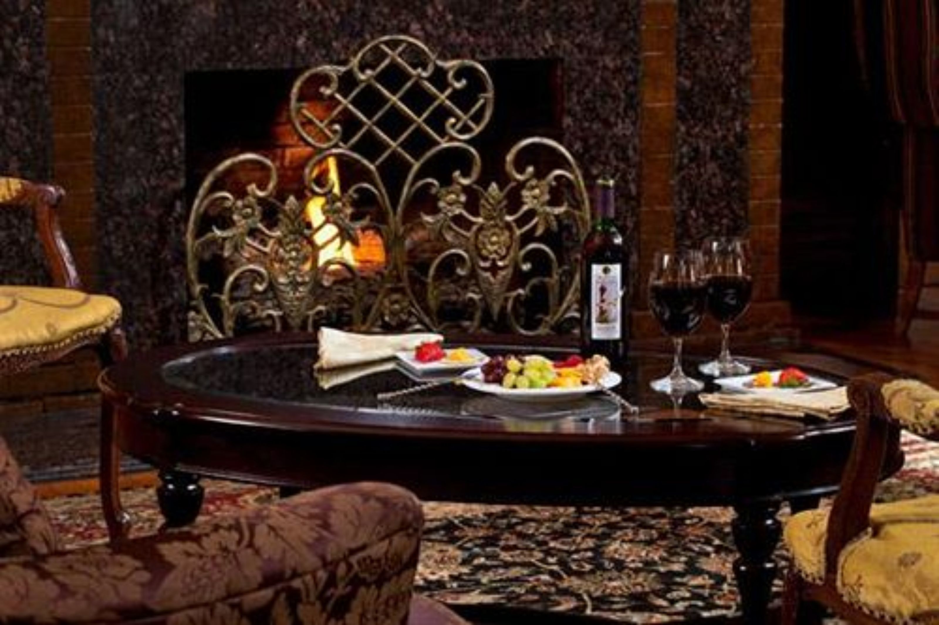 A dining area with a round table, ornate metal chairs, and a fireplace.