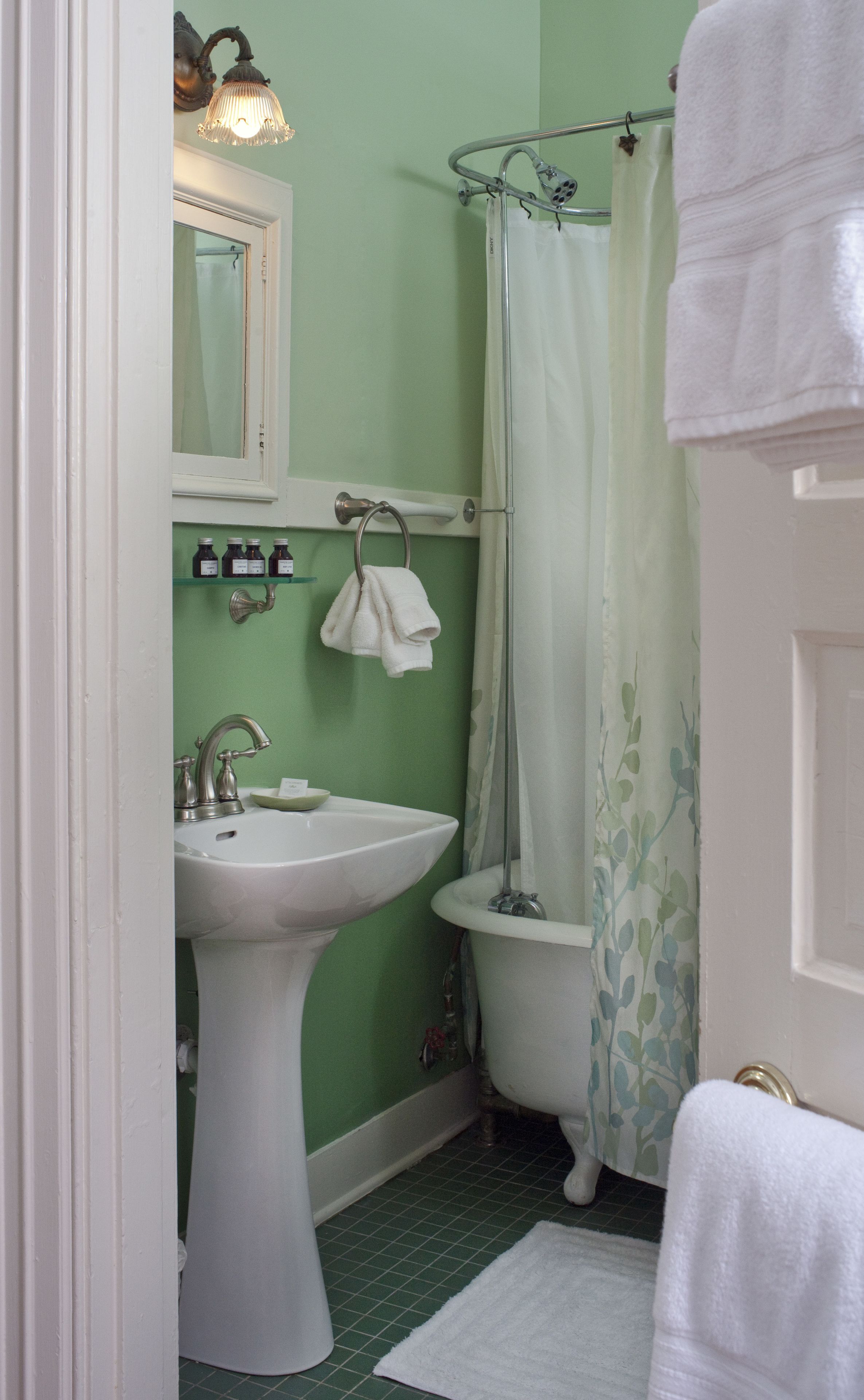Een badkamer met een wastafel op voetstuk, een toilet en een douche met gordijn.