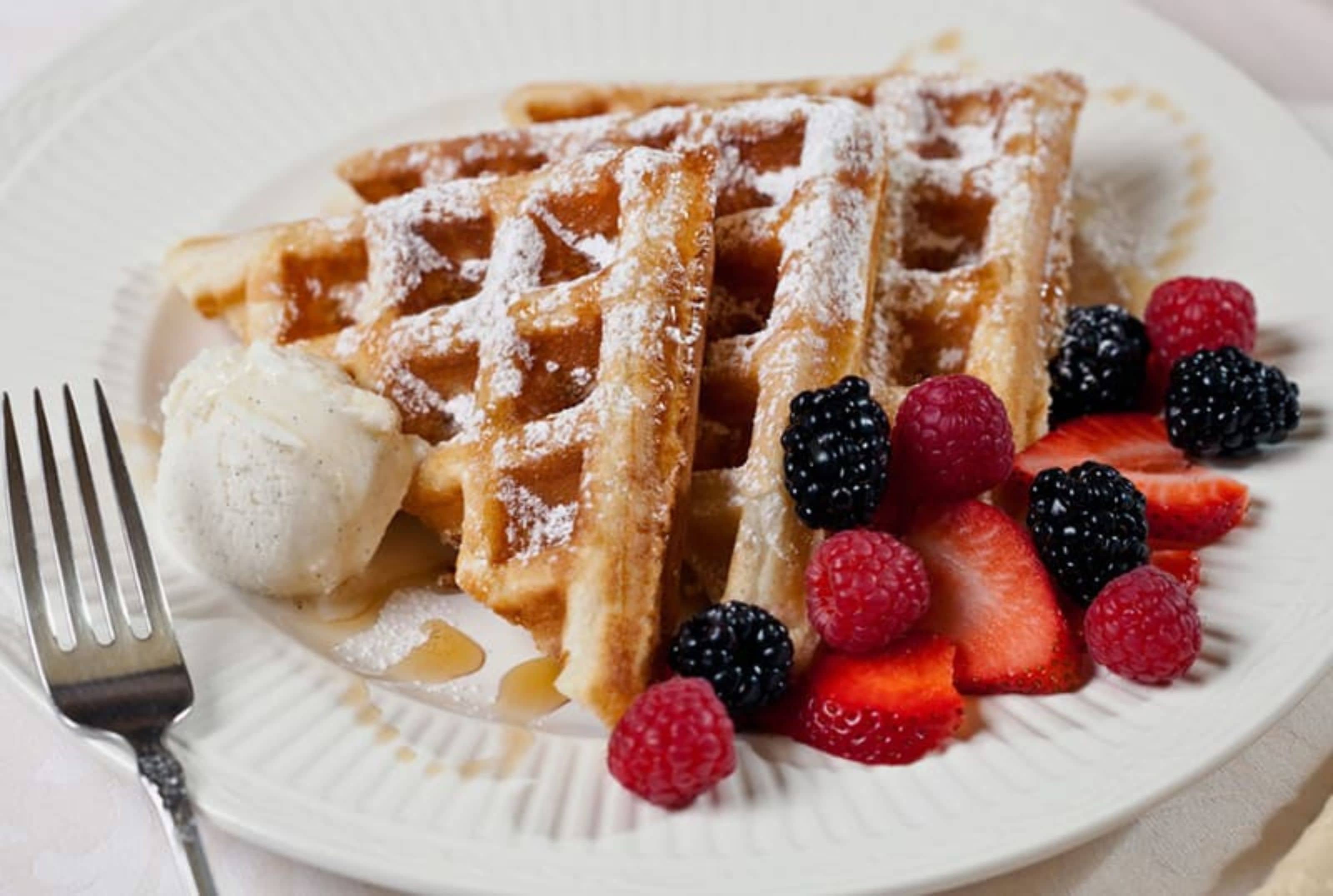 A plate with waffles, ice cream, and berries.