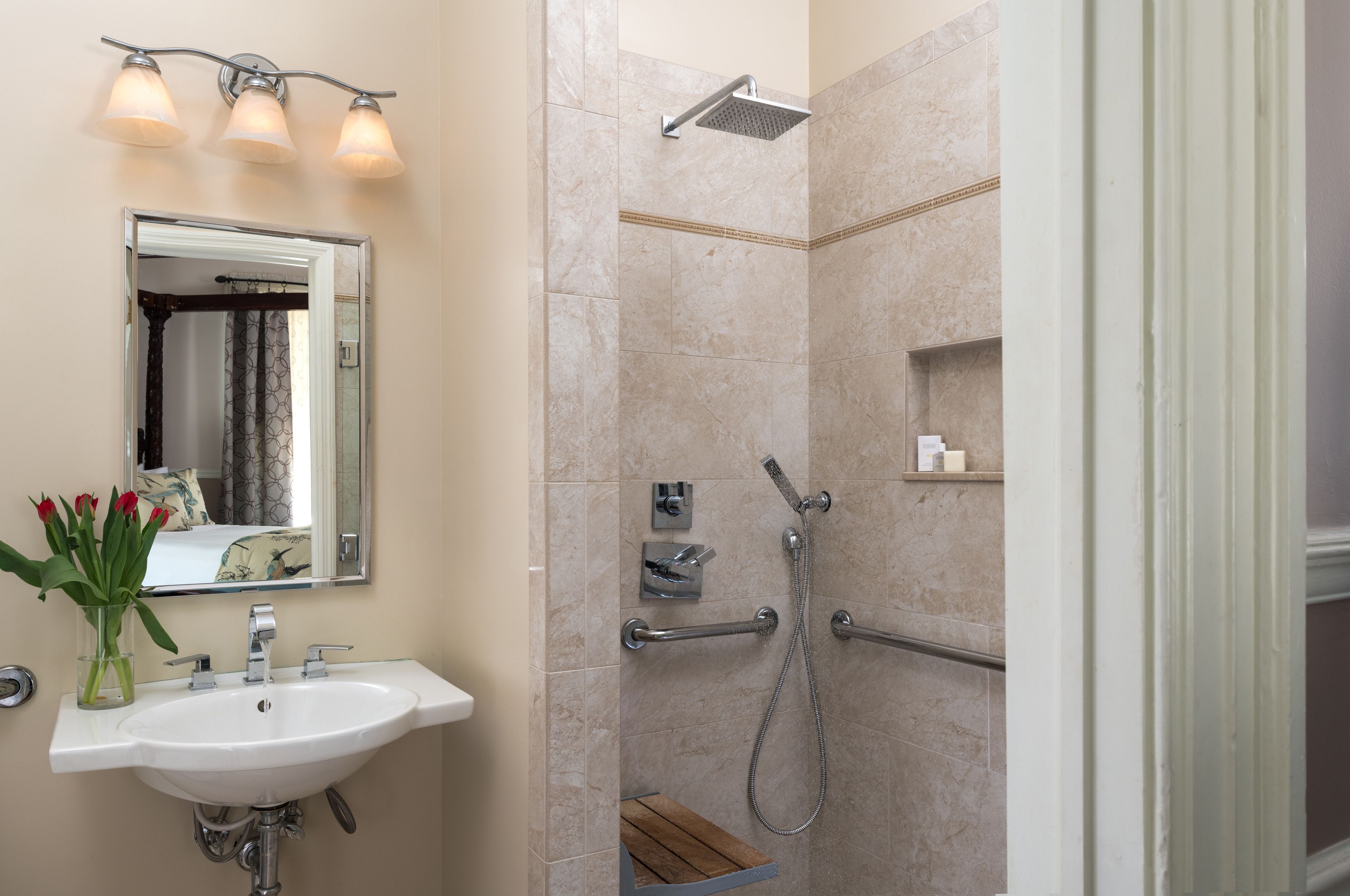 Un bagno con lavandino, specchio, doccia e porta asciugamani.