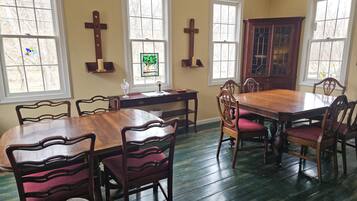 Une salle à manger avec une table et des chaises en bois, un vitrail et un buffet en bois.