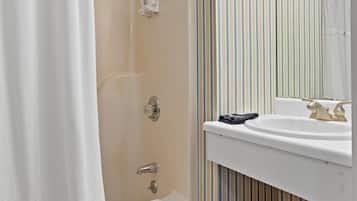 A bathroom with a shower, a bathtub, a sink, a mirror, and a wicker basket.