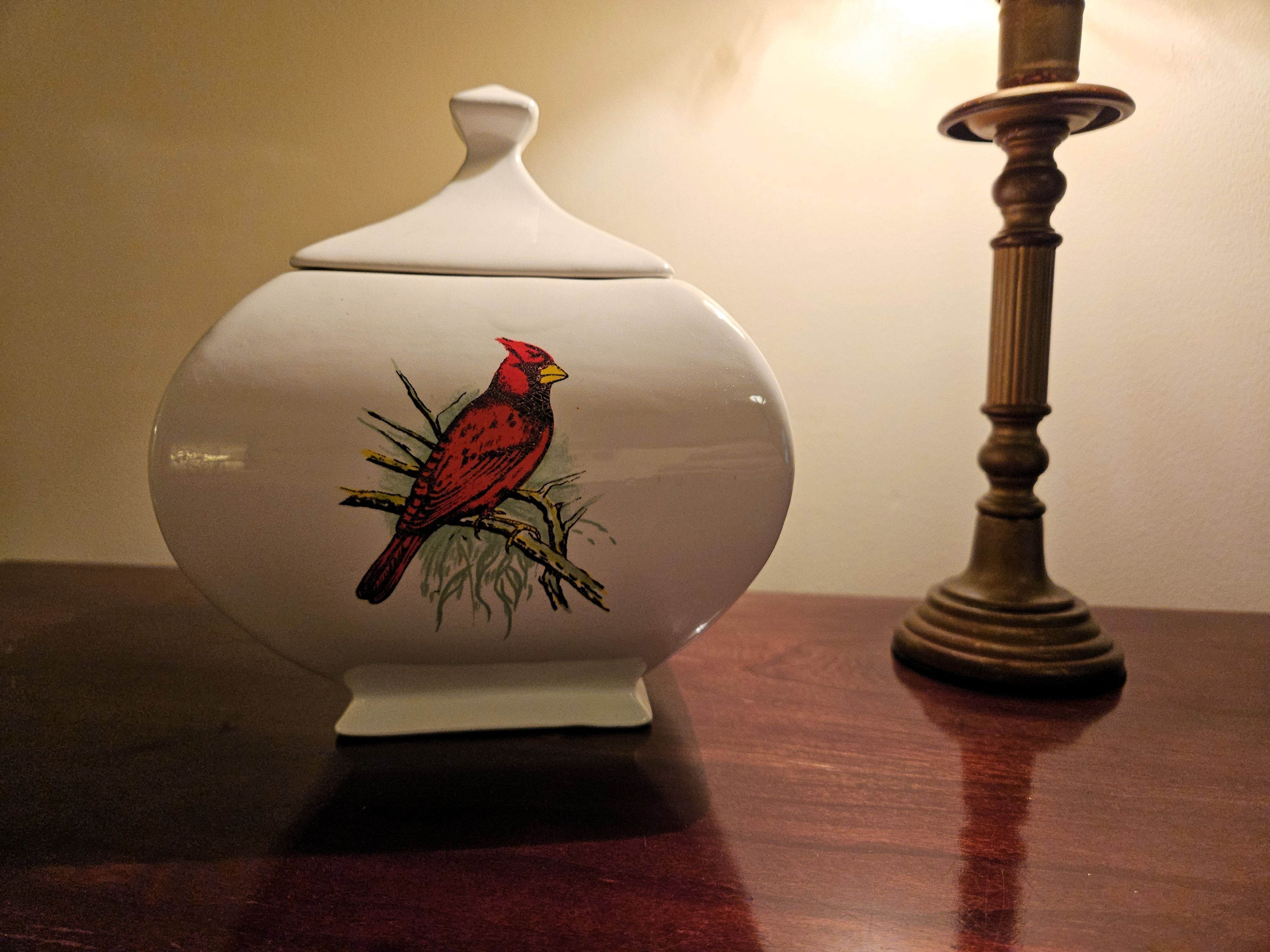 A ceramic jar with a bird design on a wooden table.