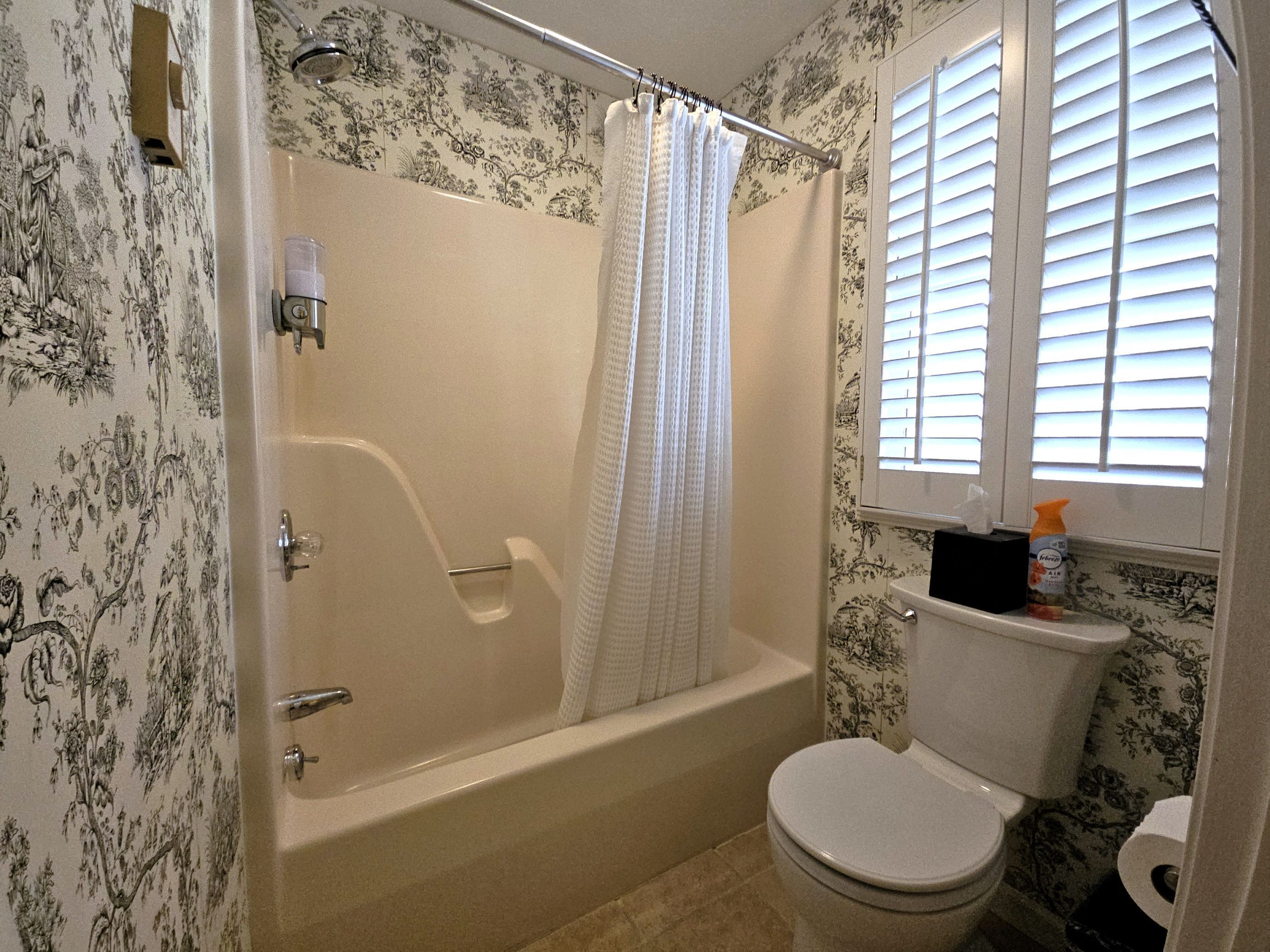 A bathroom with a bathtub, toilet, and shower curtain.