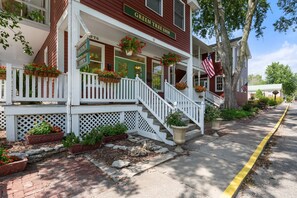 A two-story building with a porch, a staircase, and a sign indicating it's a lodging.