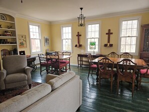 A dining area with a wooden table and chairs, a sofa, and a bookshelf.