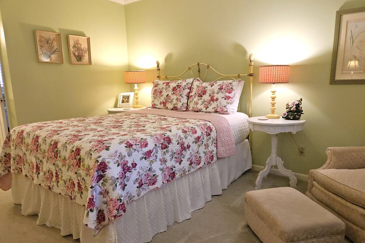 A bedroom with a bed, bedside tables, a chair, and a small table with a lamp.