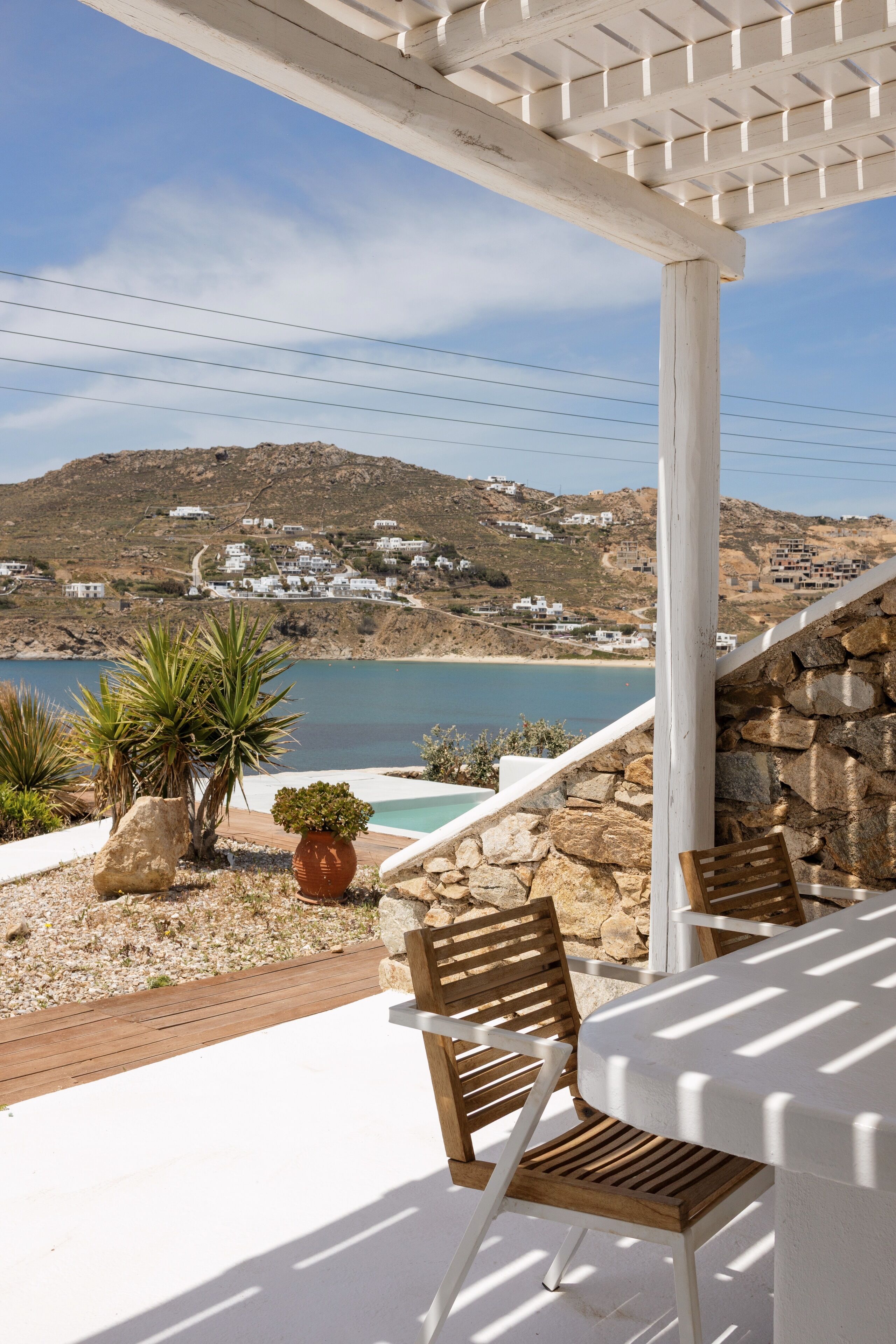 A patio with a table and chairs overlooking a coastal landscape with houses in the background.