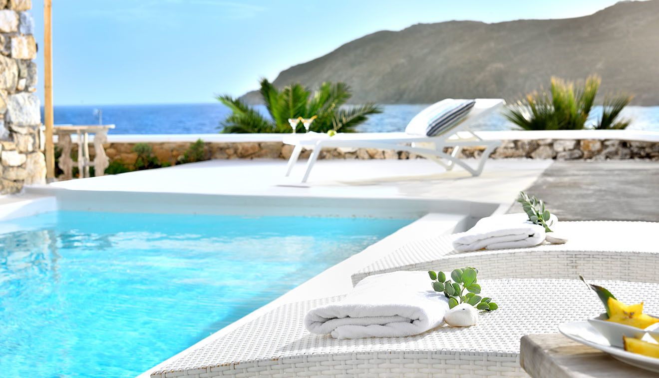 A poolside area with lounge chairs, towels, and a view of the sea.