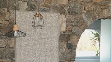 Relax in a serene bedroom with a comfortable bed, pendant lights, and a view of lush greenery through the archway.