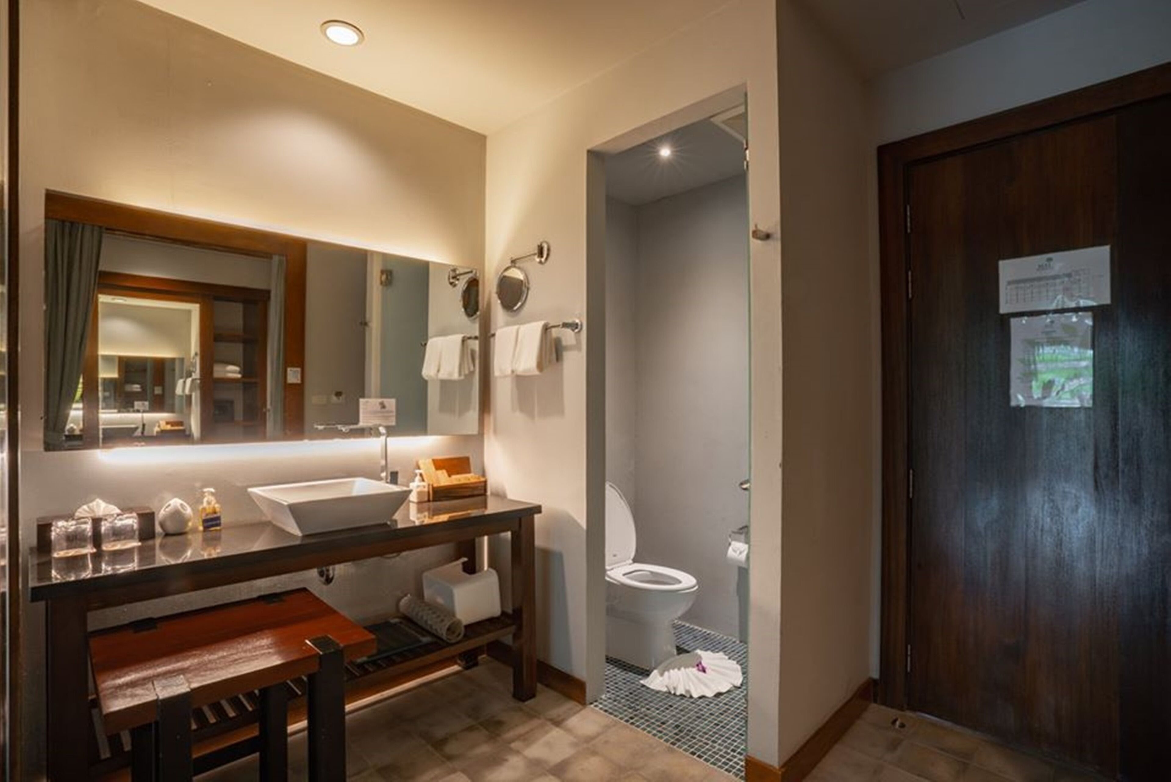 A bathroom with a large mirror, a sink, a toilet, and a shower area.