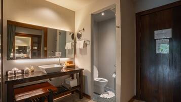 A bathroom with a large mirror, a sink, a toilet, and a shower area.